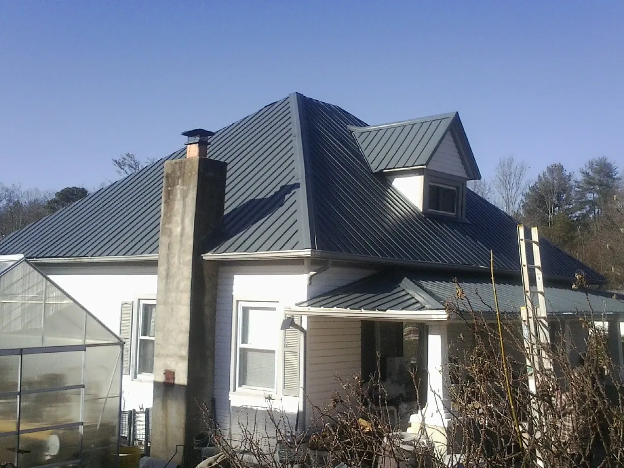 Dark blue standing seam metal roof on a white farmhouse with dormer — Slate & Tile Roof Repair by Roofing Brothers in Little Plymouth
