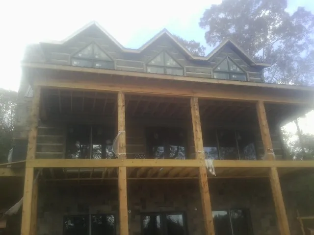Dormers and porch framing on a large log home under construction — Roof Coating work by our crew in Little Plymouth