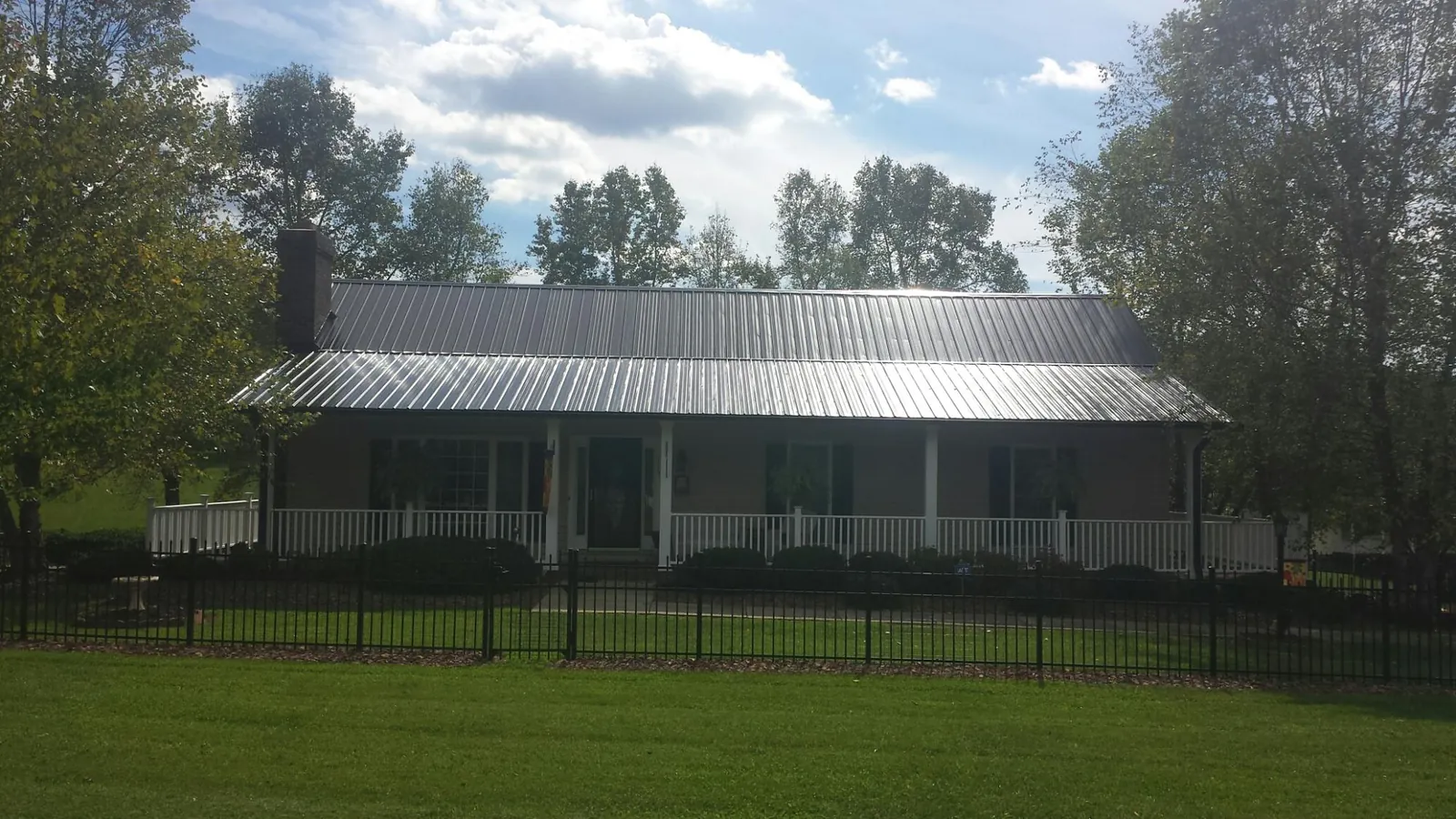 Gray metal roof on a brick ranch with a full width front porch in Little Plymouth