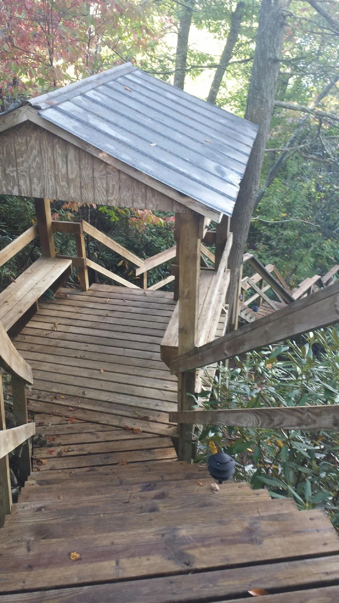 Metal roofed shelter over wooden steps on a wooded walkway — Skylight Repair & Installation work by our crew in Little Plymouth