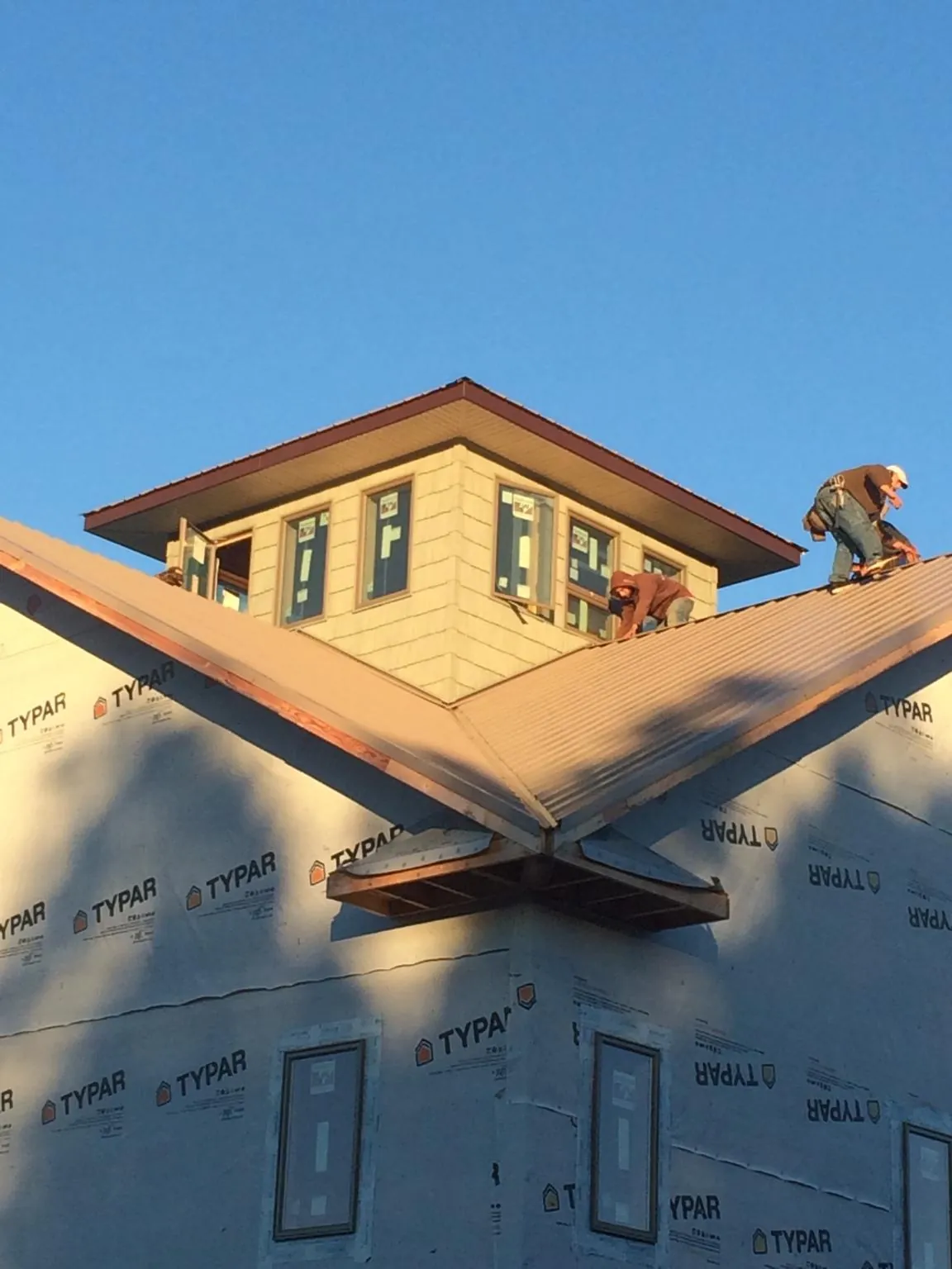 Roofers working around a rooftop cupola on a new metal roof at sunset — Roof Waterproofing in Little Plymouth by Roofing Brothers